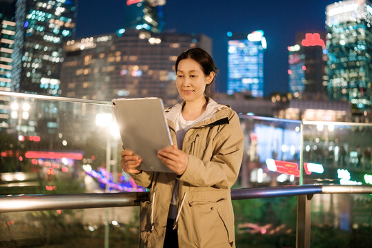自信女性在城市夜景的平板上工作