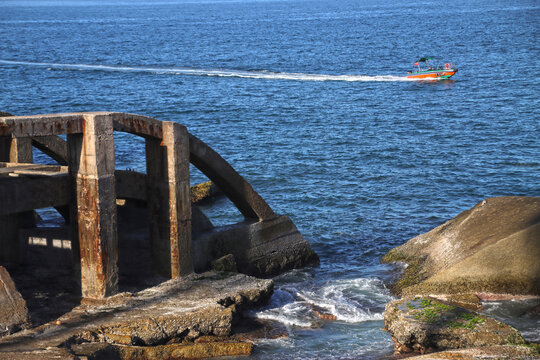 海上行驶的渔船及岸边废弃的石桥