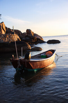 落日的余晖照射在岸边的小船上