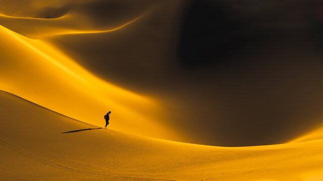 游客在黄昏的库木塔格沙漠深处