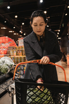 女性在超市挑选新鲜的食品放入购物框