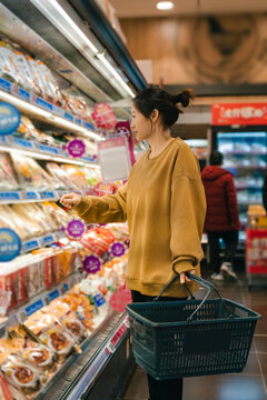 女人在超市选择货架陈列食品