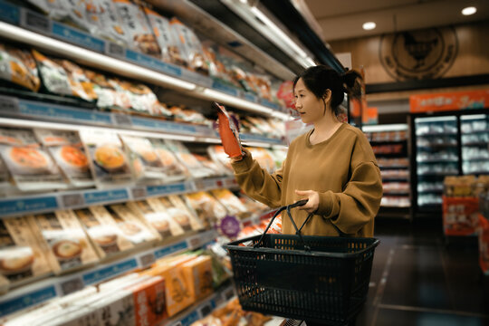 女性在超市货架专注细致查看食品