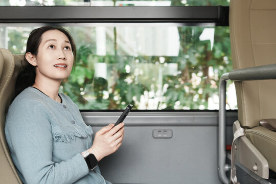女人在公共汽车用智能手机无线技术