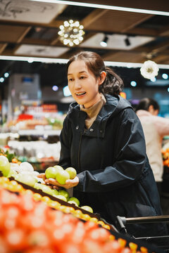 女性购物者在超市挑选新鲜水果