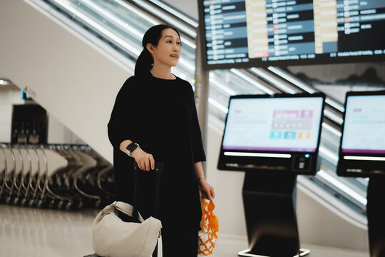 带行李箱在机场离境板上的旅行者