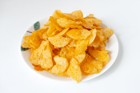 一盘白色彩绘碟子里装着一堆膨化薯片零食
