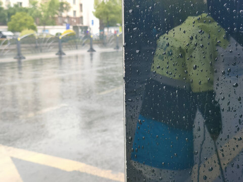 雨中玻璃反射出的环卫工人背影