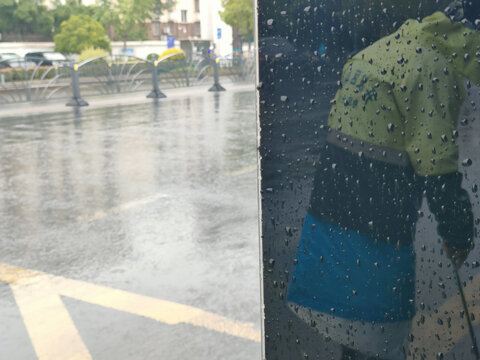 雨中玻璃反射出的环卫工人背影