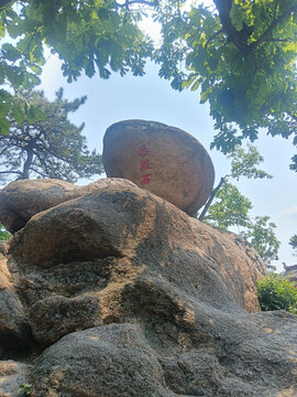 巨石屹立于绿树环绕间辽宁千山无根石