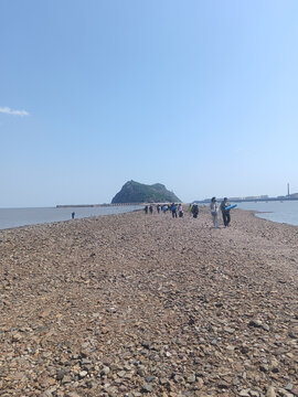 海边碎石滩上的漫步人群锦州笔架山