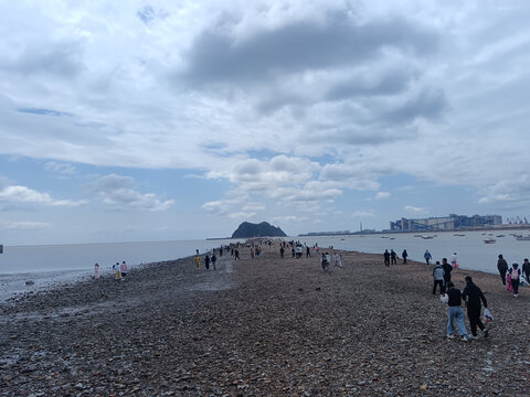 海滨碎石滩上的休闲人群锦州笔架山