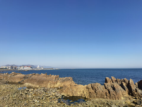 海边嶙峋礁石与远处城镇