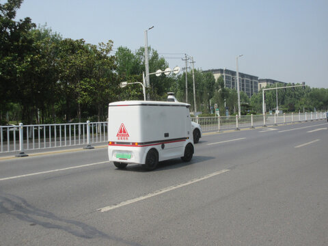 道路上行驶的白色无人配送车