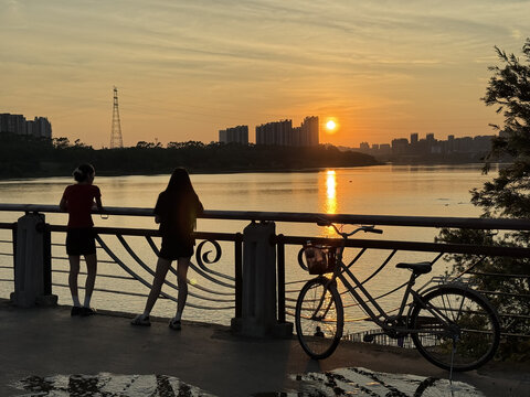夕阳下河畔的二人与单车