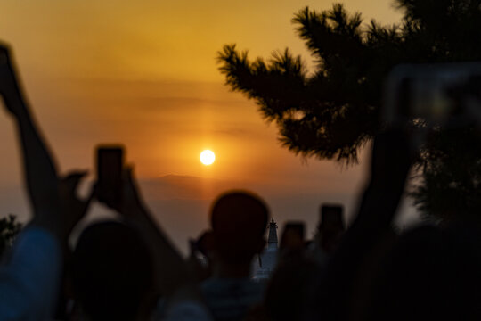 众人夕阳下举手机拍摄