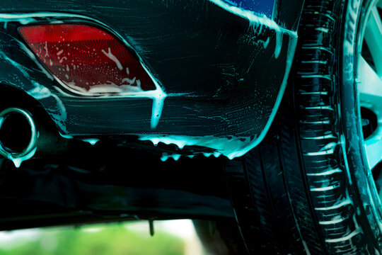 特写蓝色SUV汽车洗车画面，白色泡沫洗车液。汽车护理业务。汽车清洗和抛光前的打蜡服务。车辆清洁服务带