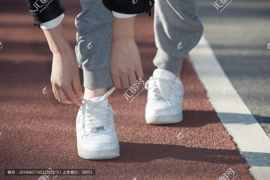 在跑道上系鞋带的人