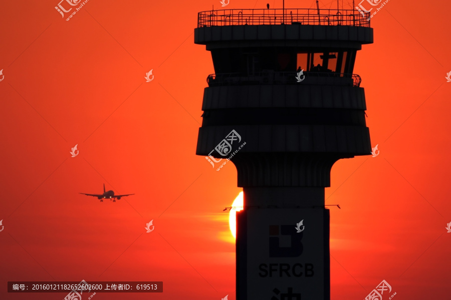 夕阳中的塔台和降落的飞机