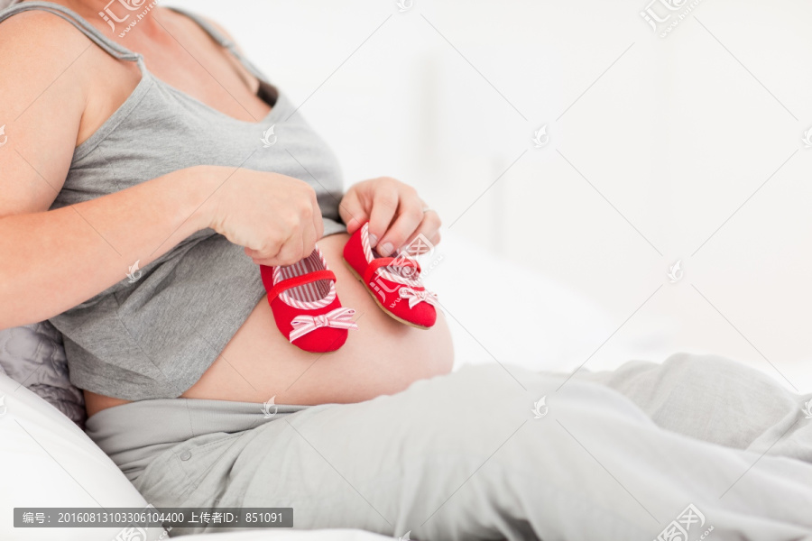 拿着婴儿鞋的孕妇