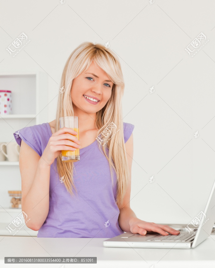 边喝橙汁边用电脑的女人