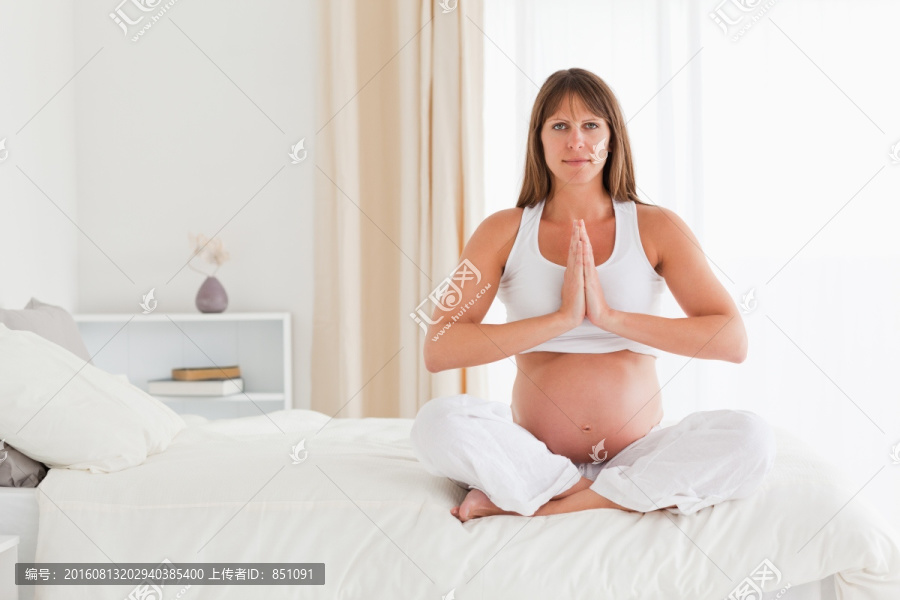 年轻的孕妇在床上做瑜伽