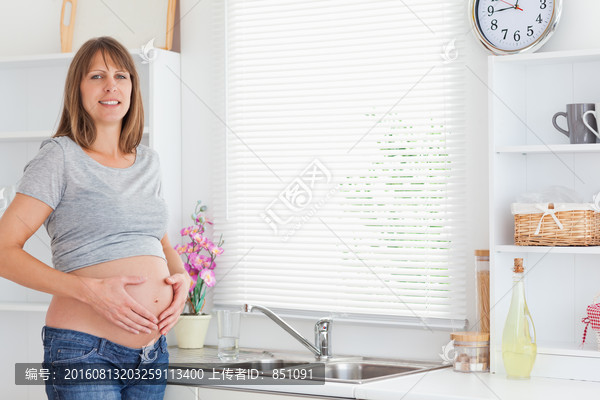 孕妇在厨房里抚摸自己的肚子