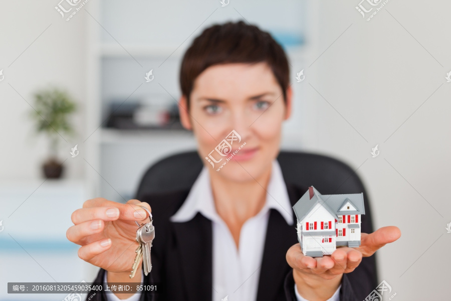 女秘书拿着微型房子和钥匙