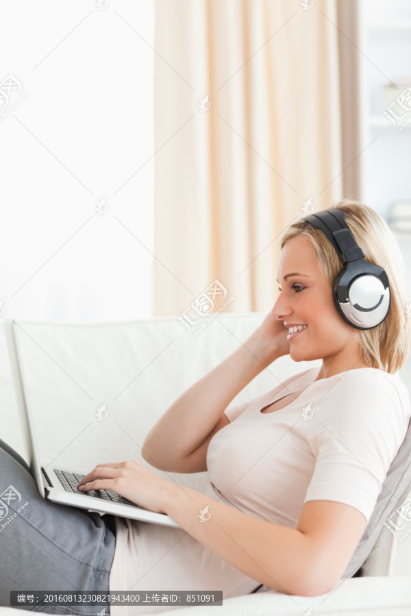 在沙发上玩电脑听音乐的女人