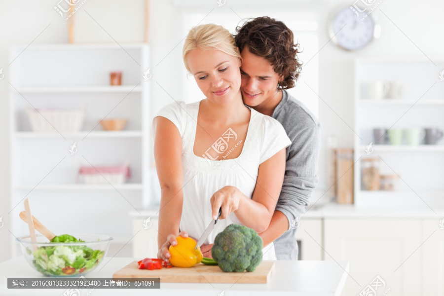 丈夫环抱住正在切菜的妻子