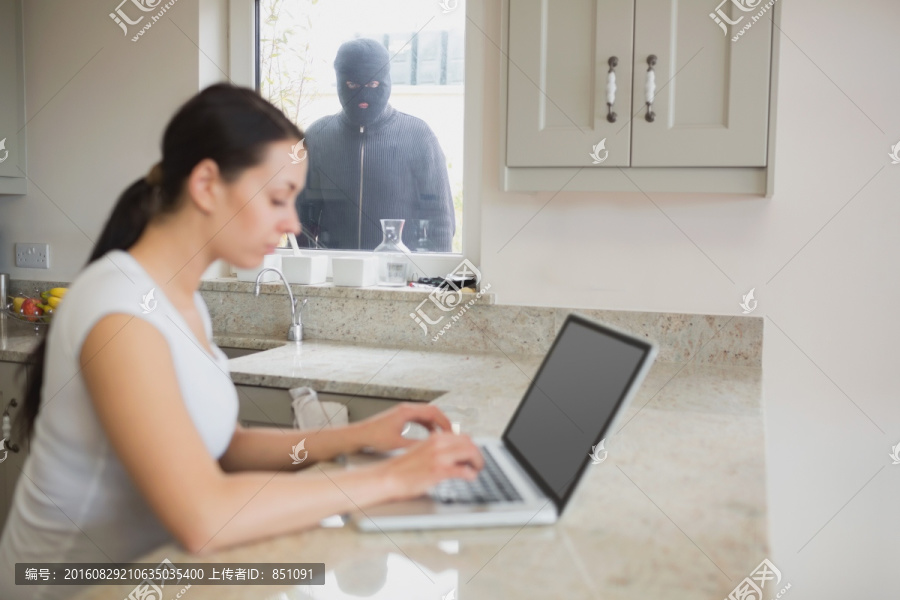 小偷透过窗户观察正在上网的女人