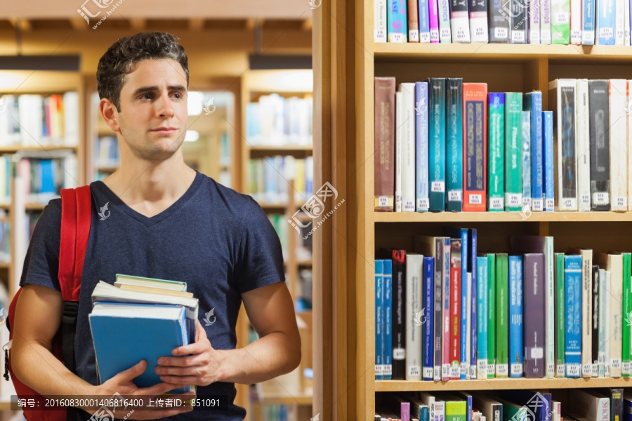 学生站在图书馆抱着一堆书