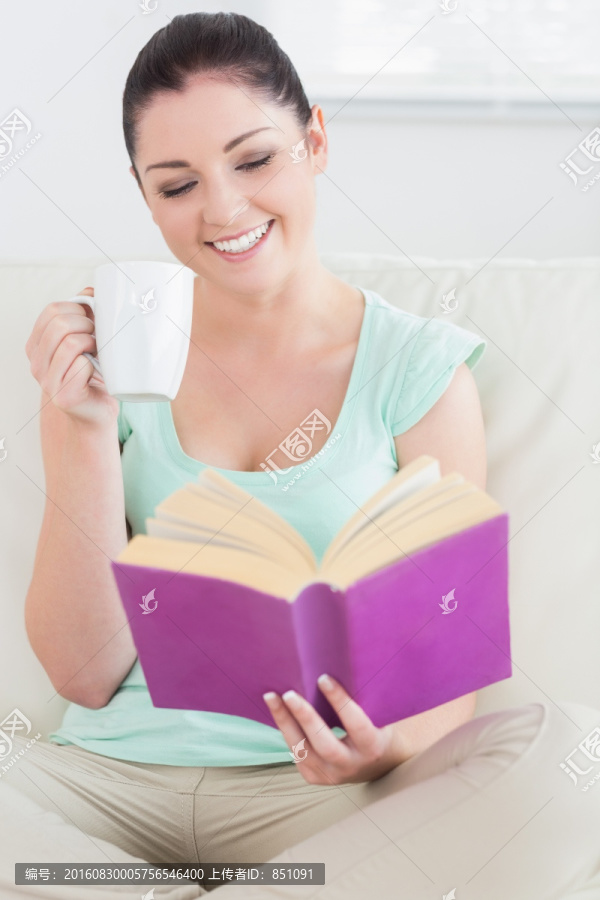 坐在沙发上看书喝茶的女人