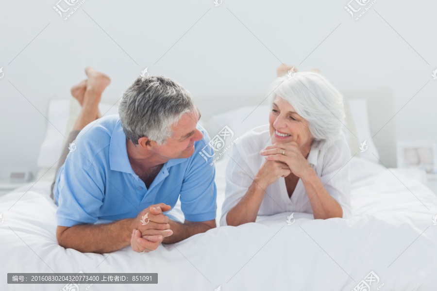 趴在床上微笑着聊天的夫妇