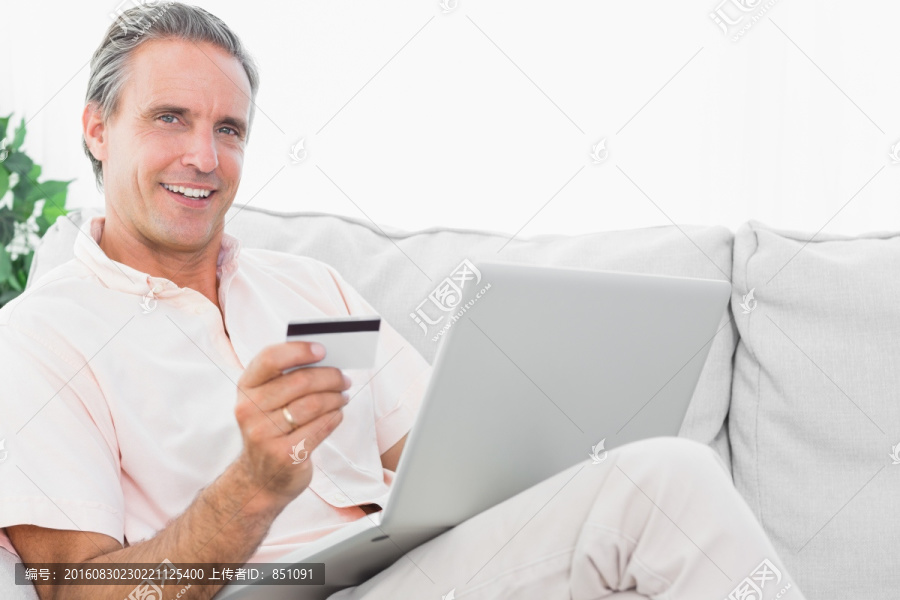 男子在沙发上使用电脑网上购物
