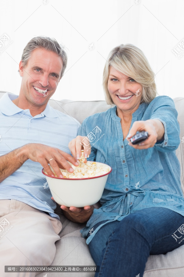 两人在沙发上看电视和吃爆米花