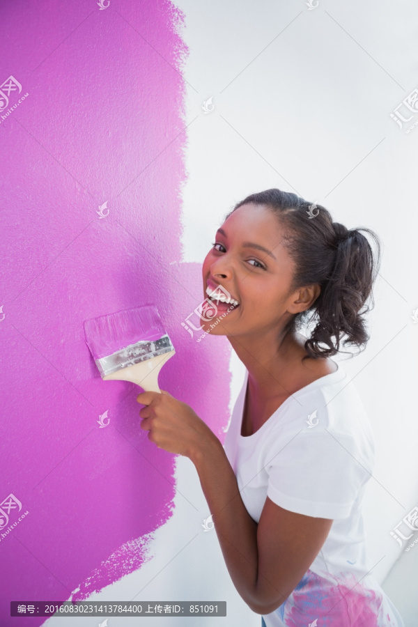 开心的年轻女子在粉刷墙壁