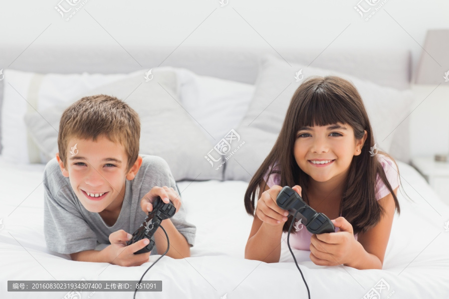 趴在床上的兄妹在家里玩电子游戏