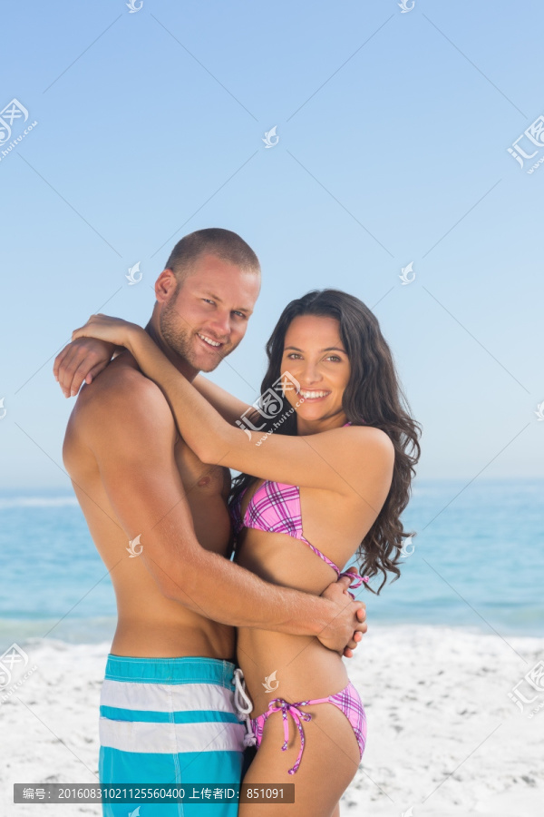微笑的年轻夫妇在沙滩上拥抱