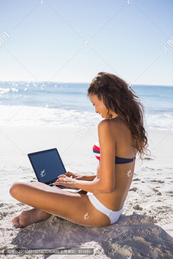 在沙滩上使用笔记本电脑的女人