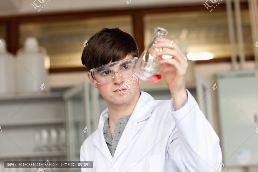 在实验室看锥形瓶里的液体的男人