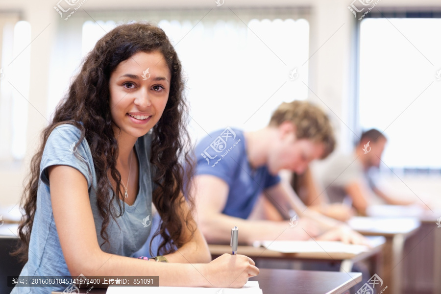 微笑的女学生在教室里考试