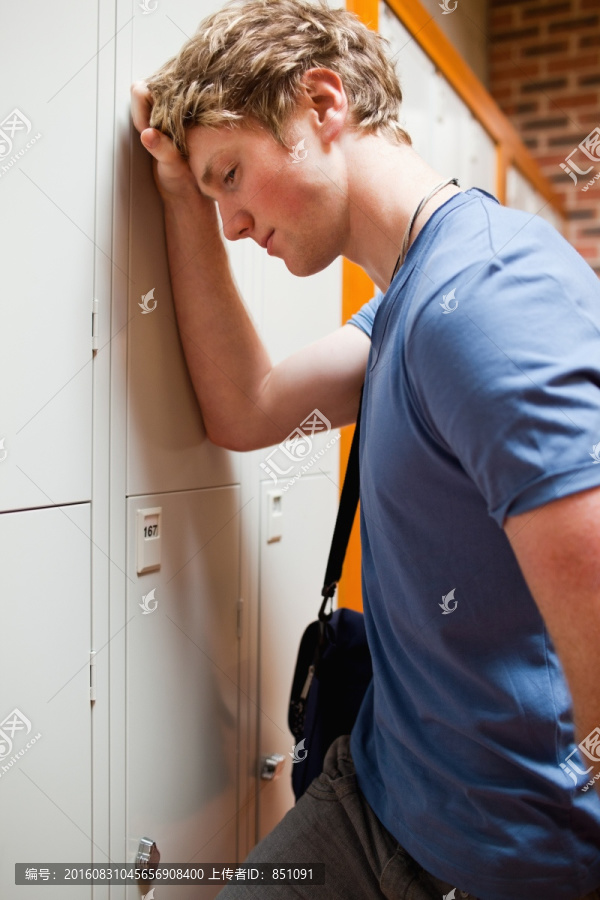 一个男学生靠在更衣柜上