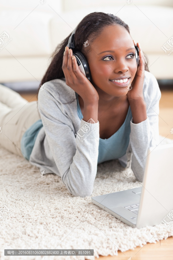微笑的女人爬地毯上听音乐