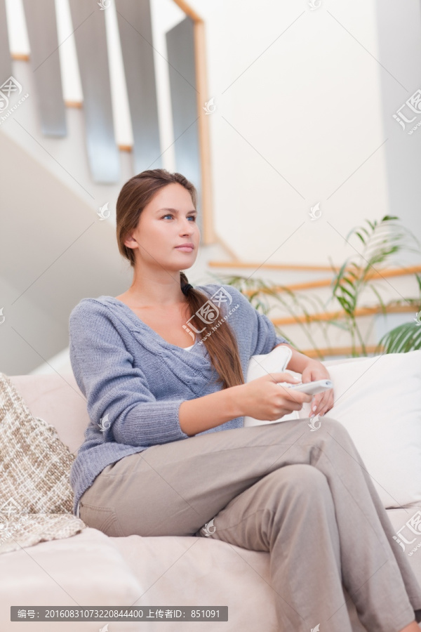 女人在客厅里使用遥控器看电视