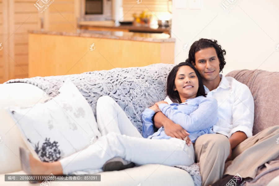 快乐的年轻夫妇一起坐在沙发上