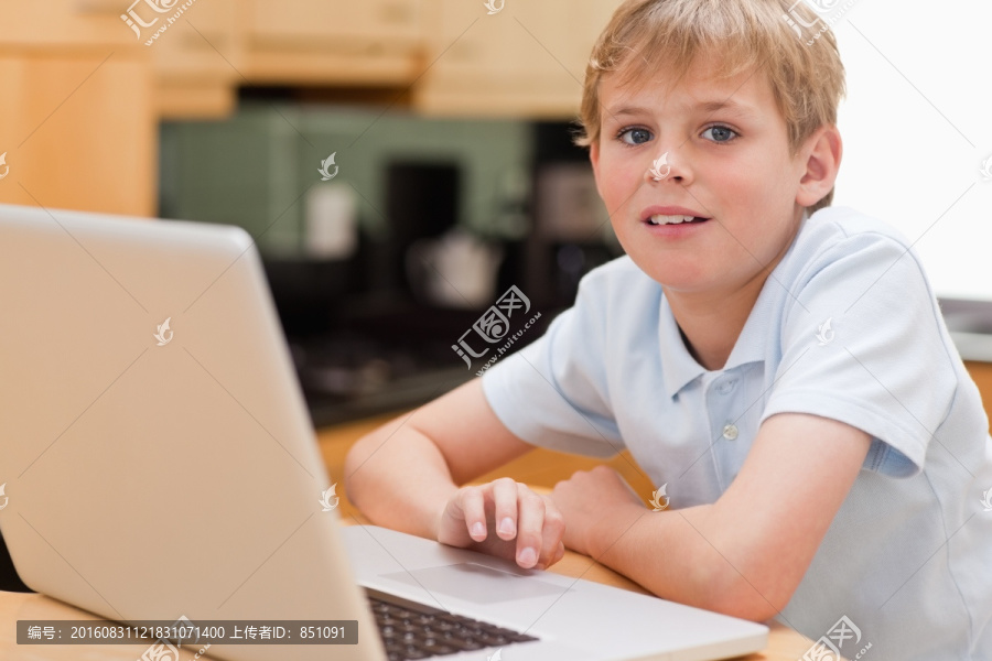 男孩在厨房里使用一台笔记本电脑