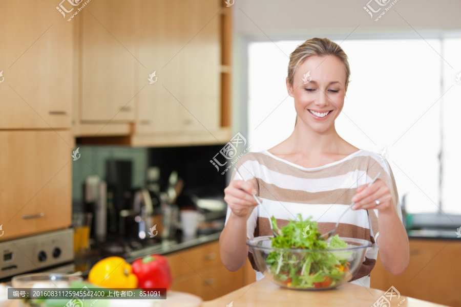 微笑的女人在搅拌沙拉