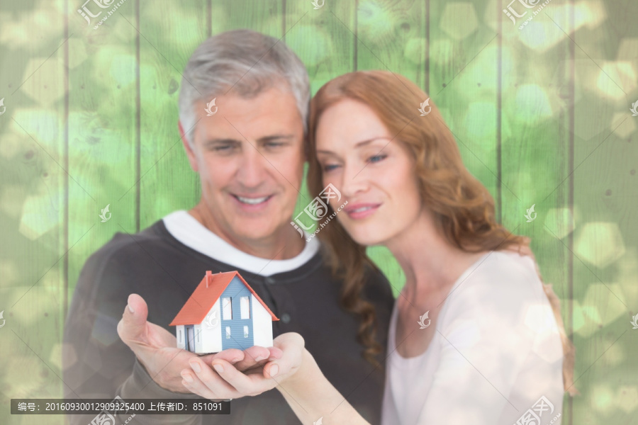 微笑着拿着房屋模型的夫妇