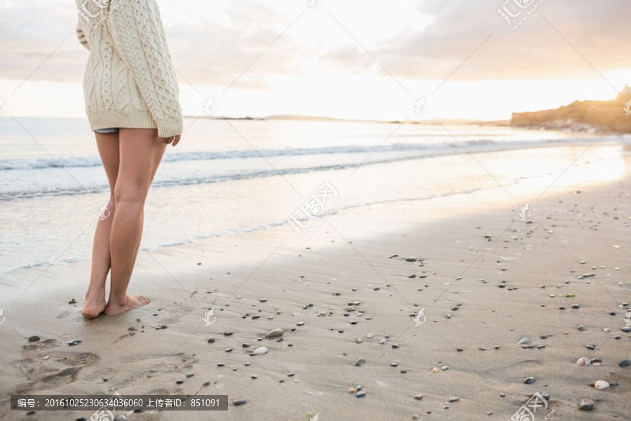 穿着毛衣的女人站在沙滩上